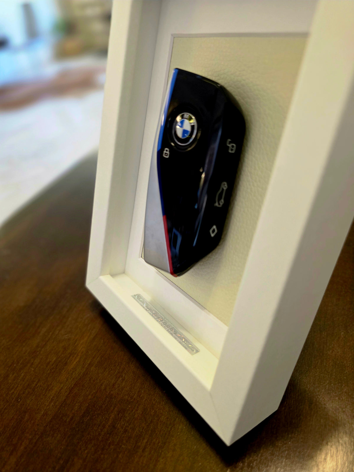 BMW key fob in a white frame on a wooden surface