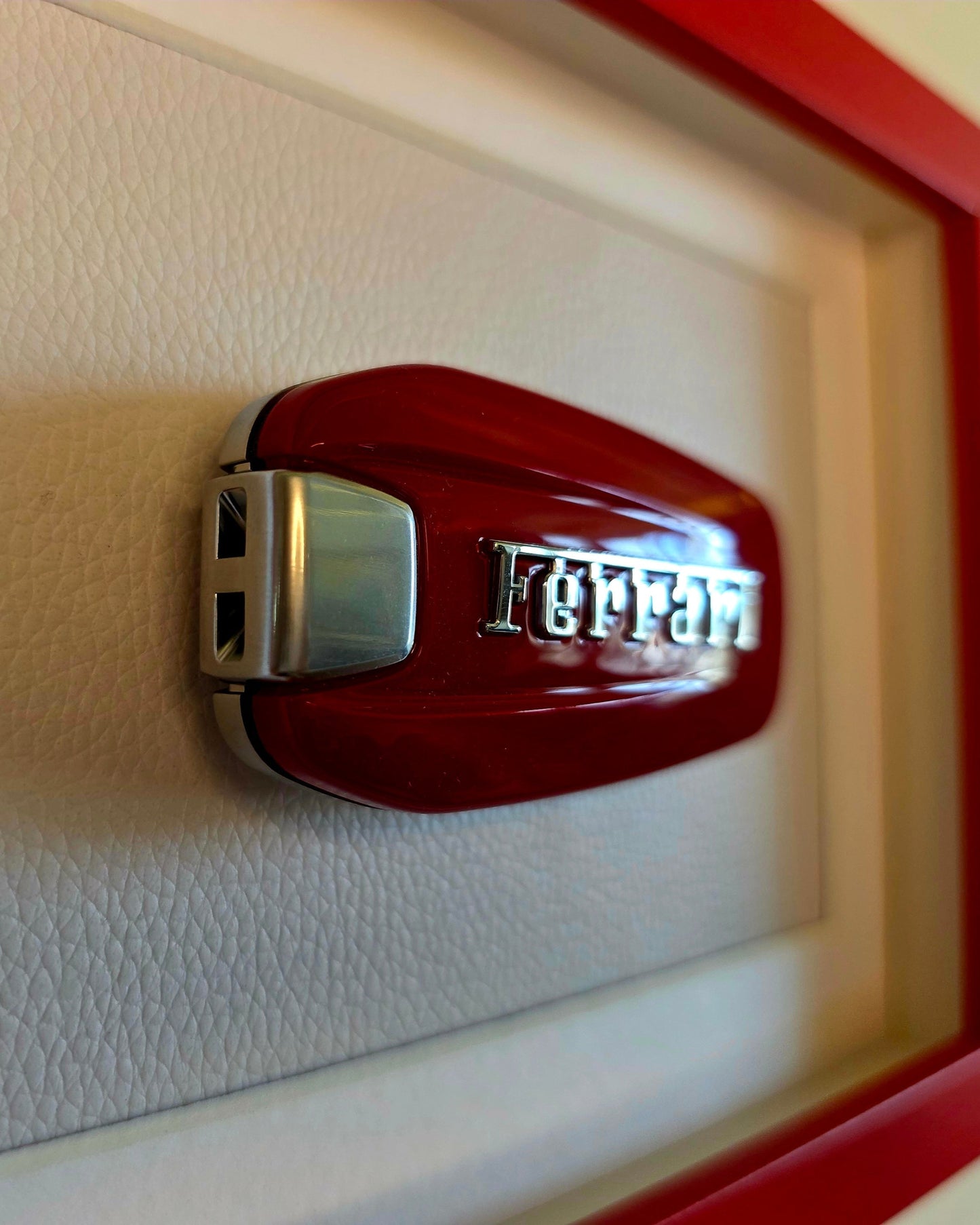 Red Ferrari logo on a textured white surface with a red border