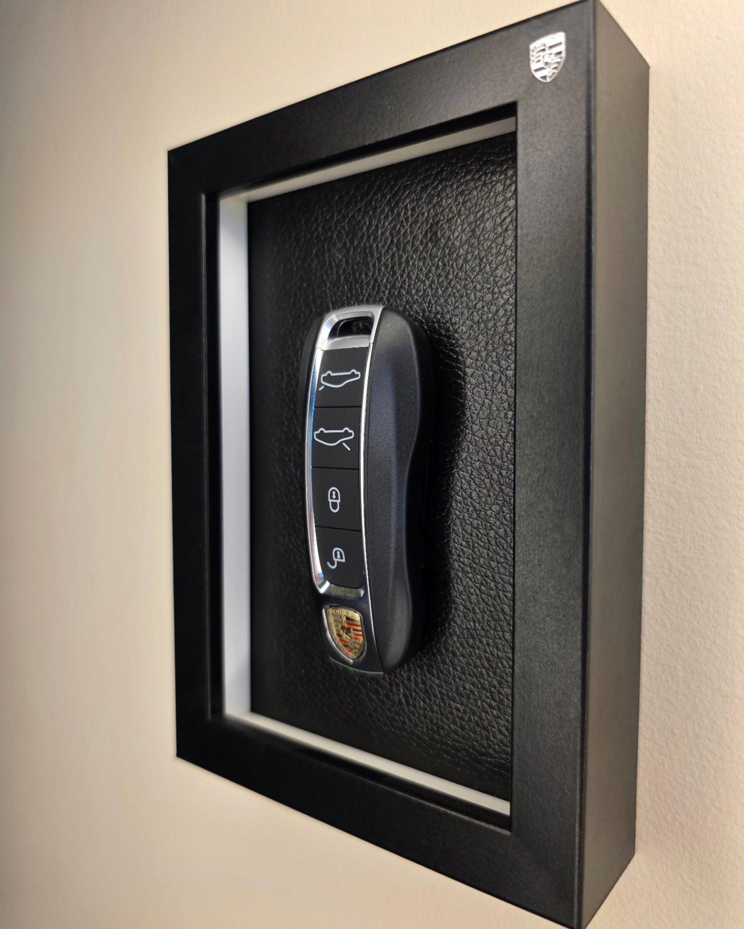 Car key in a black display case on a beige wall