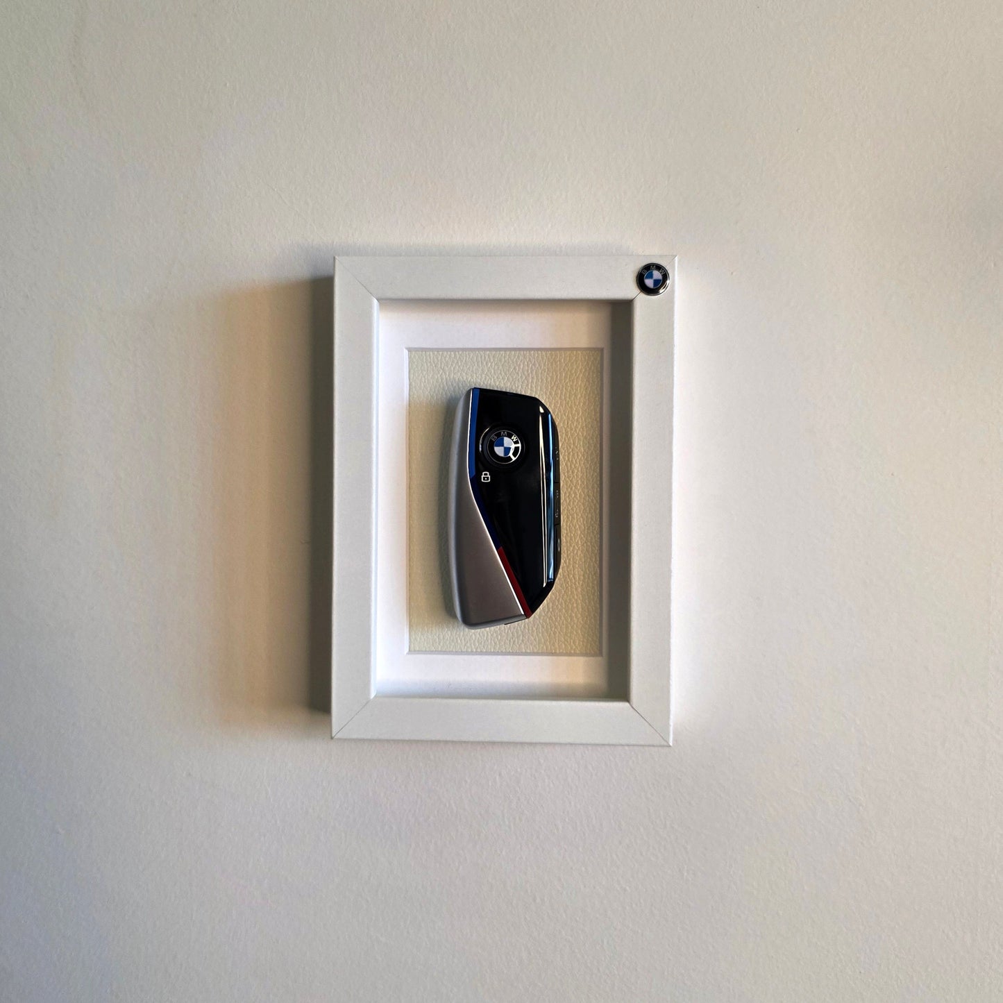 Framed picture of a car key on a white wall
