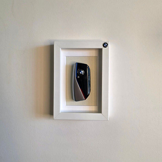 Framed picture of a car key on a white wall