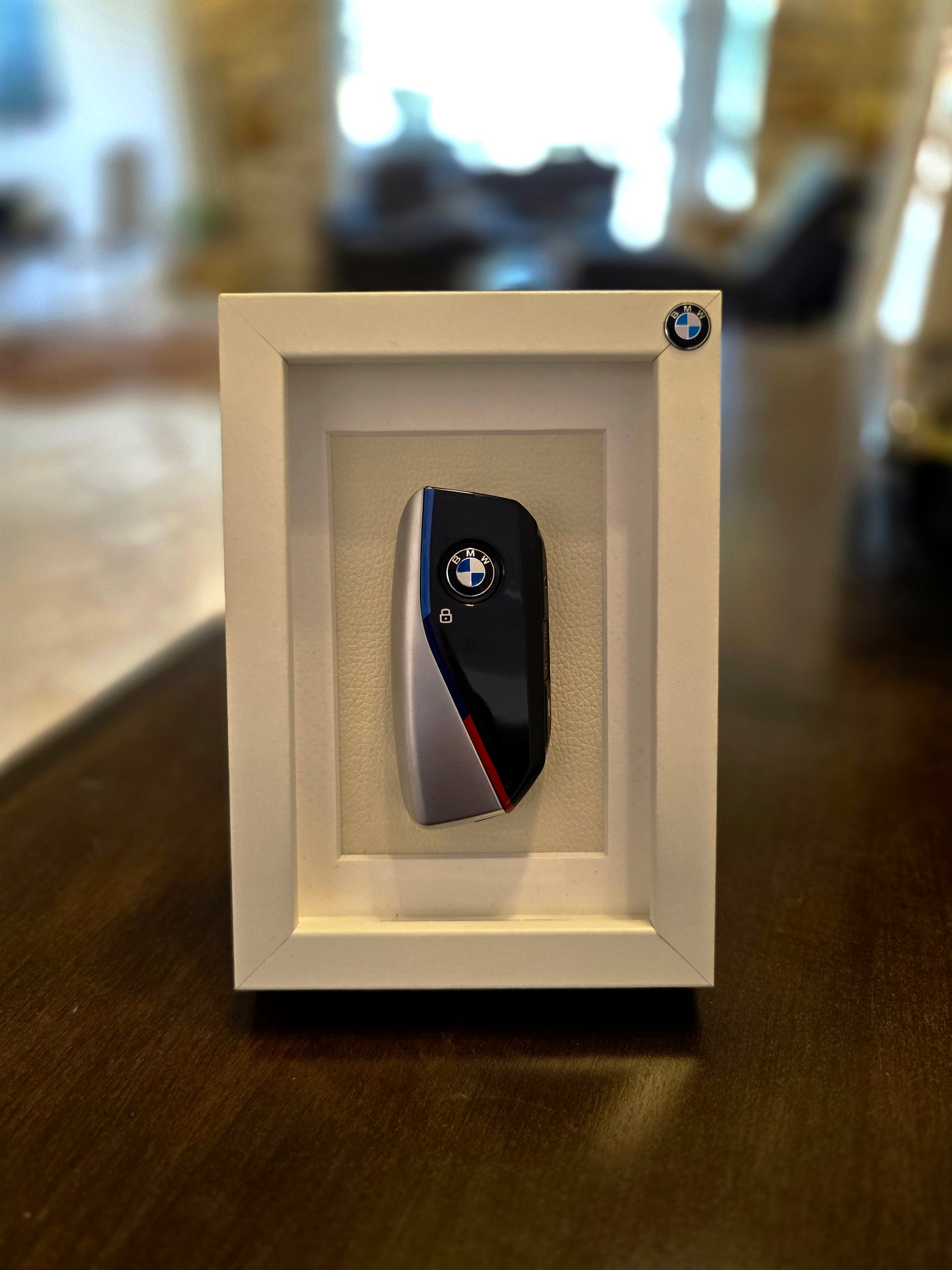 BMW key fob in a white frame on a wooden surface