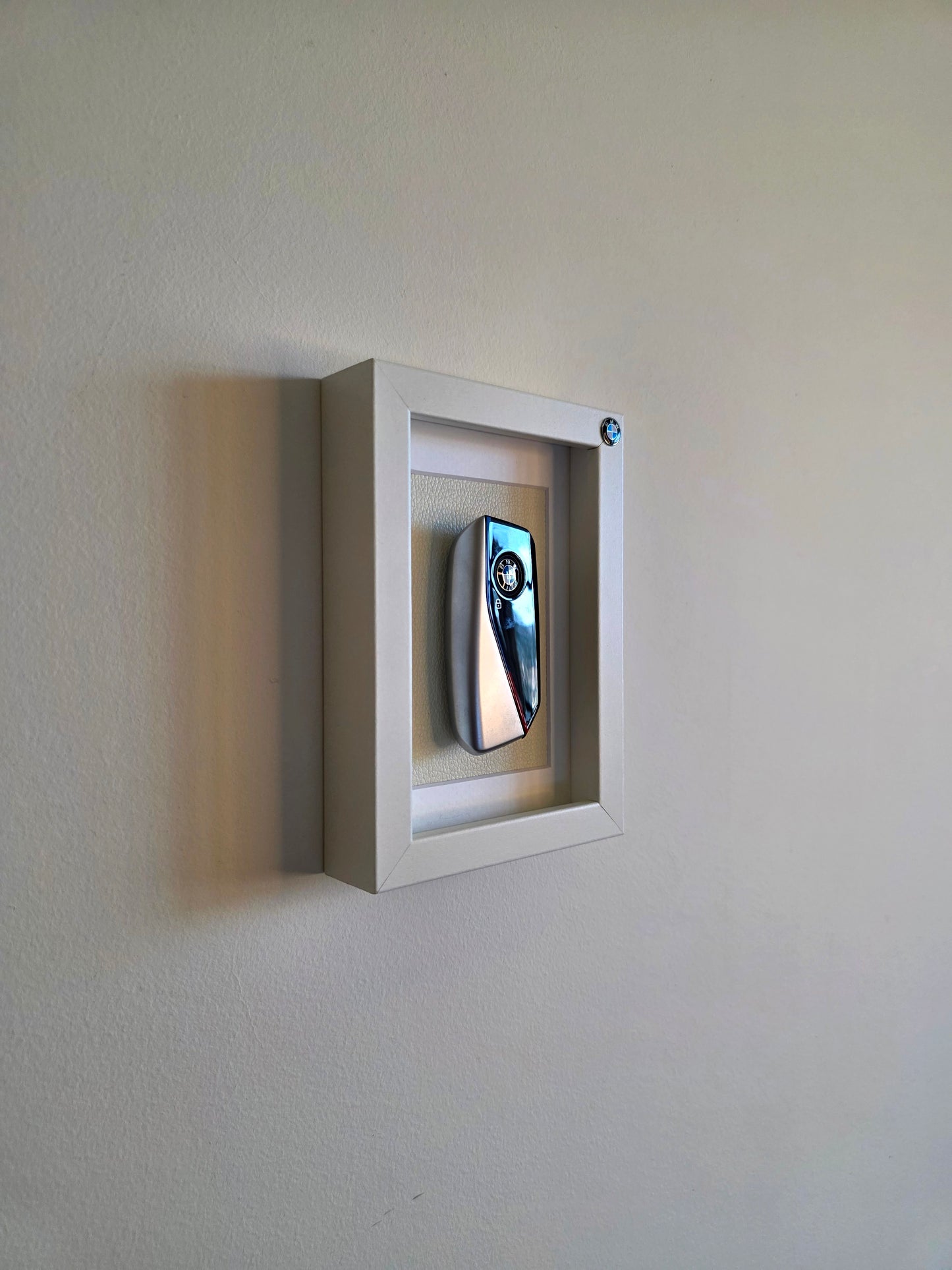 Small rectangular mirror in a white frame mounted on a plain wall.