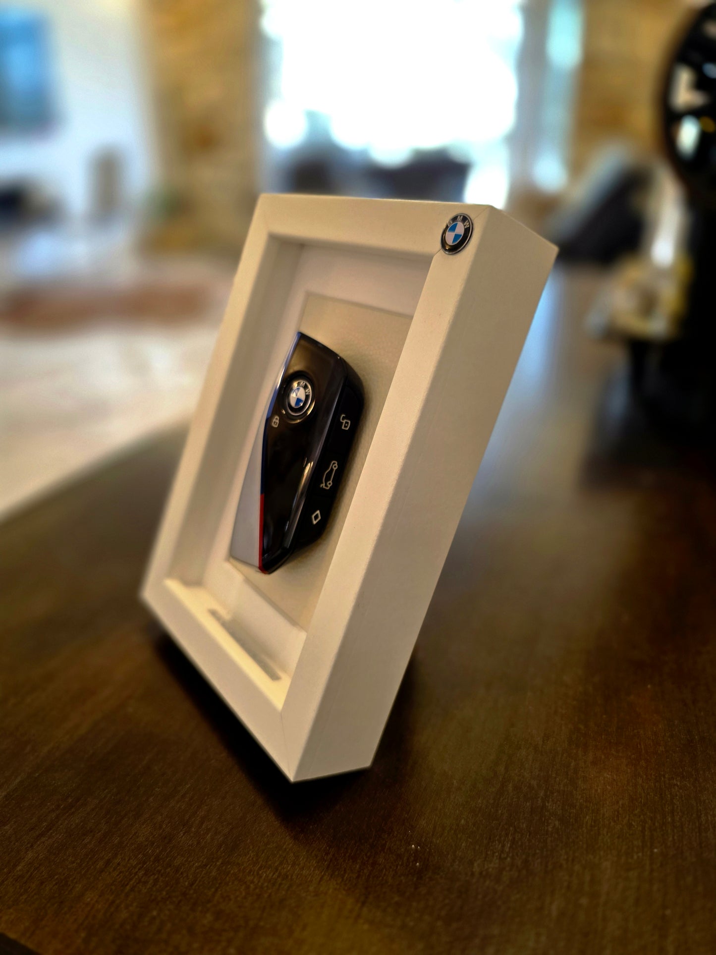 Car key fob in a white frame on a wooden surface with a blurred background