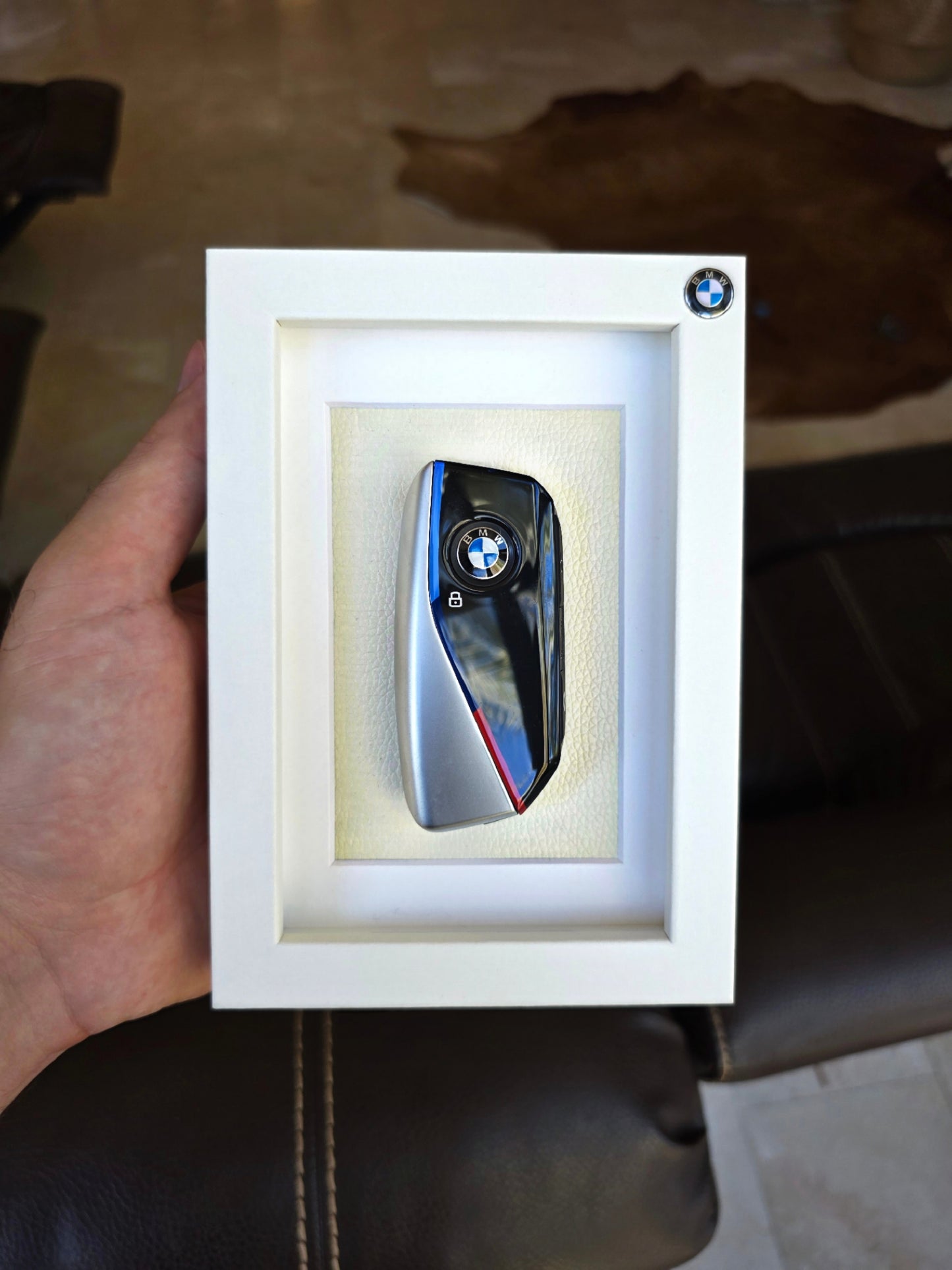 BMW key fob in a white box held by a hand on a brown surface