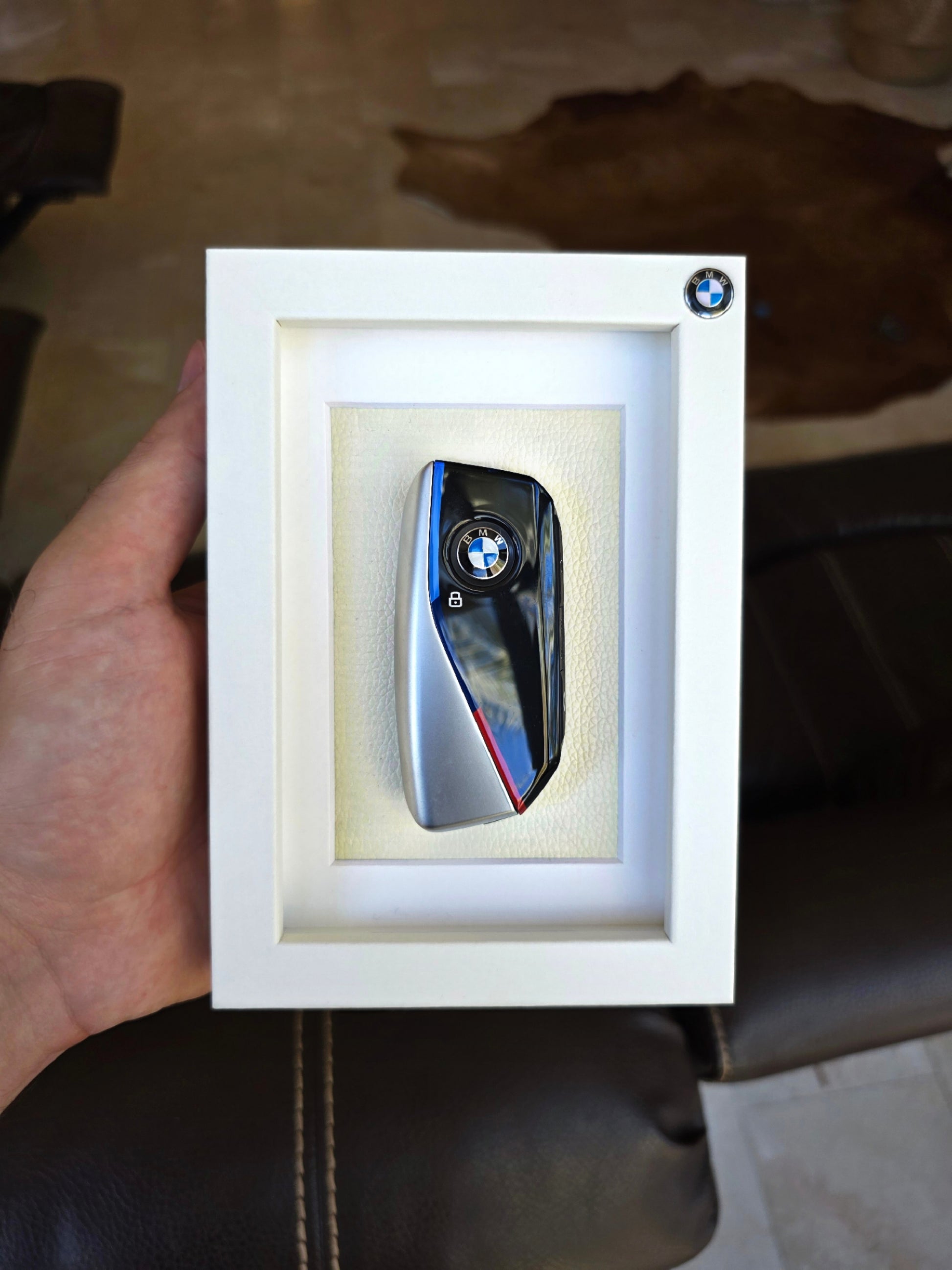 BMW key fob in a white box held by a hand on a brown surface